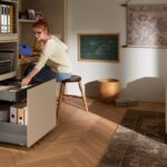 Béžová pracovná zostava s hlbokými sivými zásuvkami na zakladače a kancelárske potreby v modernom interiéri.