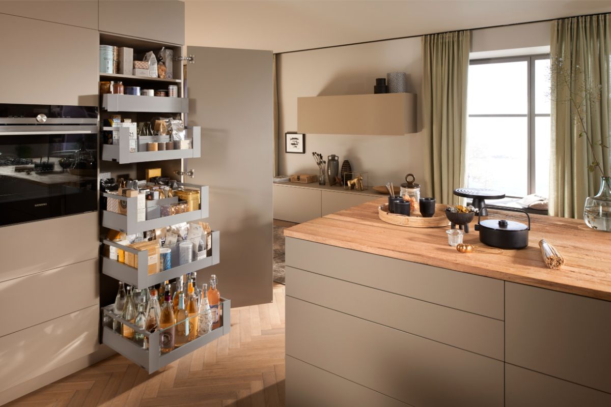 Otvorená béžová potravinová skriňa so sivými výsuvnými zásuvkami.