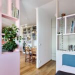 Byt s bielou a ružovou policovou zostavou, drevenou podlahou a bielou polpriečkou.