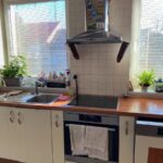 Klasická kuchynská zóna s nerezovým digestorom, varnou doskou a oknami so svetlými žalúziami.