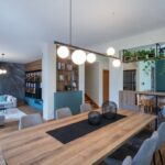 Otvorený obytný priestor s drevenou podlahou, petrolejovou komodou a prepojenou kuchyňou v škandinávskom štýle.