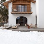 Vila s exteriérom alpských chát a bielou fasádou, dreveným obkladom. a terasou s posedením.