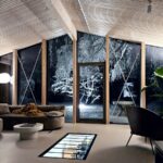 Moderný interiér s dreveným latkovým stropom, preskleným podlahovým priezorom do podzemnej vinotéky a tmavou oblou sedačkou.