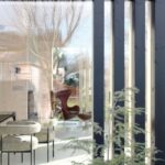 Pohľad cez veľkoformátové presklenie do interiéru s dreveným obložením stien a moderným zariadením.