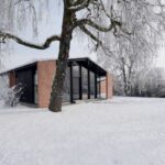 Zrekonštruovaný dom s tehlovými múrmi a veľkým presklením v čiernych rámoch.