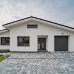 Moderný rodinný dom z exteriéru s bielou fasádou a oknami s antracitovým rámom.