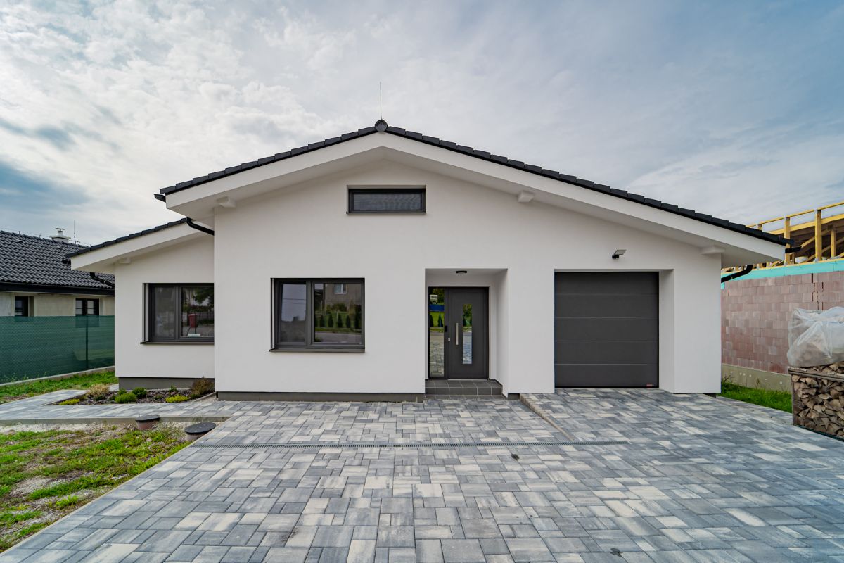 Moderný rodinný dom z exteriéru s bielou fasádou a oknami s antracitovým rámom.