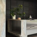 Antikorový a mramorový kuchynský ostrov so zásuvkami a dekoráciami.