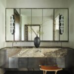 Široké mramorové dvojumývadlo, veľké nástenné zrkadlo a antikorové skrinky v minimalistickej kúpeľni.