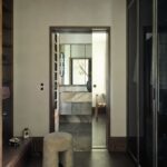 Walk-in šatník so skriňou, dizajnovou stoličkou a vstupom do kúpeľne.