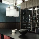 Jedáleň s modernou vinotékou, čiernym stolom pod modrou stenou s tmavým dreveným soklom.