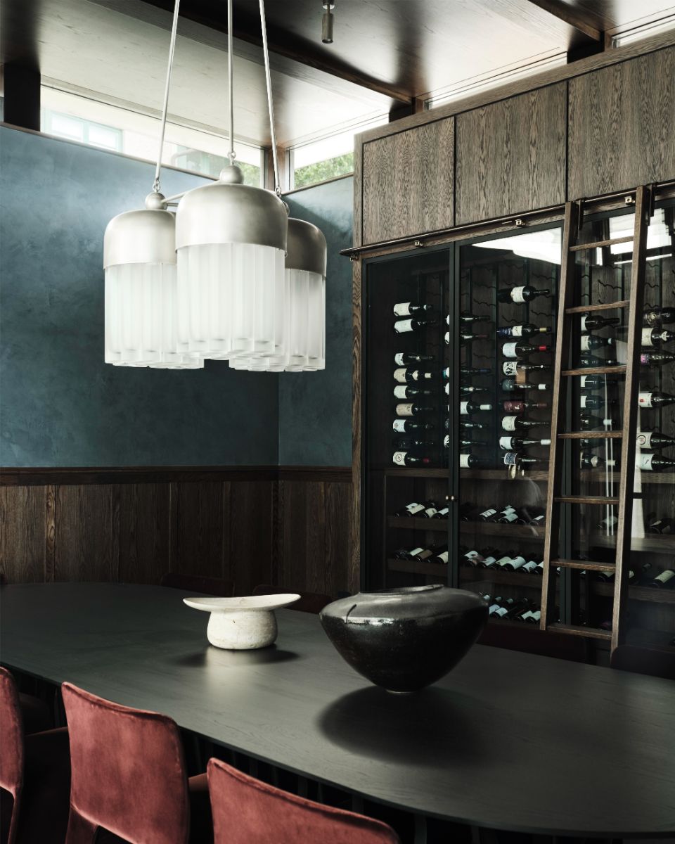 Jedáleň s modernou vinotékou, čiernym stolom pod modrou stenou s tmavým dreveným soklom.