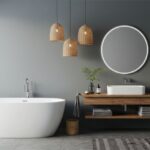 Moderná oválna vaňa, drevená podumývadlová konzola, okrúhle svietiace zrkadlo a tri prútené lustre na sivej stene