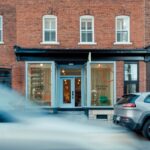 Svetlomodrý vstup do budovy s tehlovou fasádou, a veľkými výkladmi.