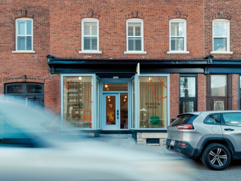 Svetlomodrý vstup do budovy s tehlovou fasádou, a veľkými výkladmi.