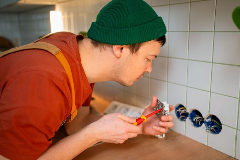 Mladý elektrikár pri inštalácii zásuviek do kuchynskej zásteny.