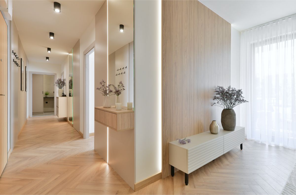 Chodba s nízkou skrinkou a samonosnou policou s kvetmi.