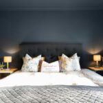 Spálňa s tmavými stenami aj stropom a s posteľou s čiernym čalúneným čelom.