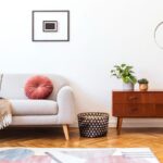 Interiér s parketovou podlahou, svetlou sedačkou a tmavou nízkou skrinkou na nožičkách.