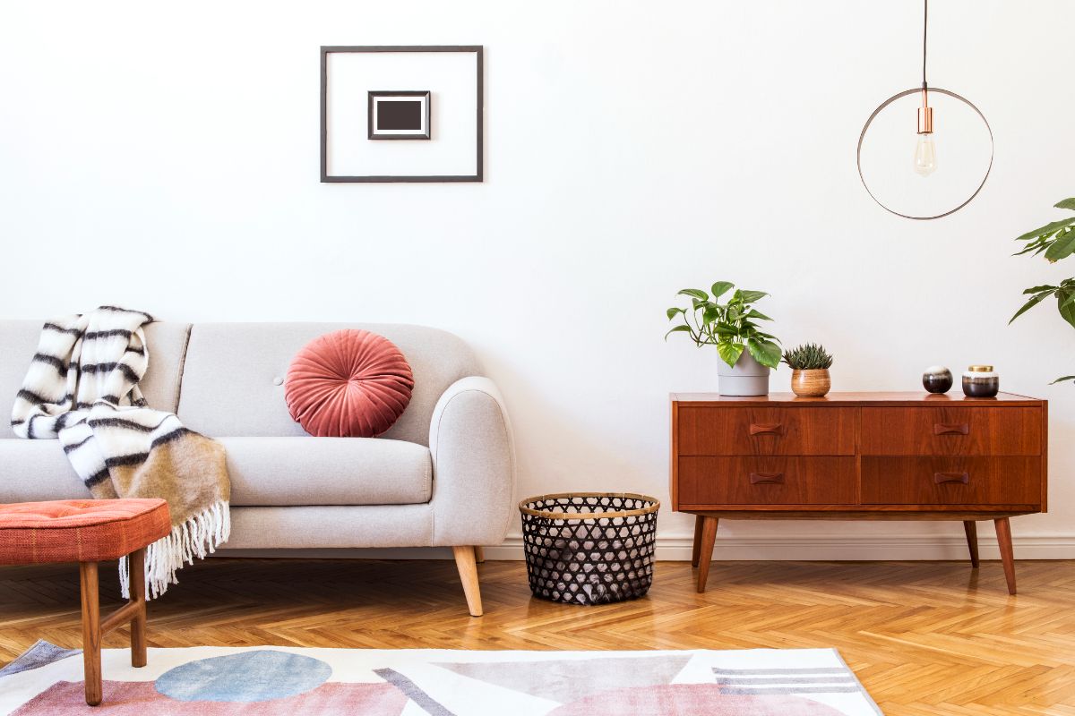 Interiér s parketovou podlahou, svetlou sedačkou a tmavou nízkou skrinkou na nožičkách.