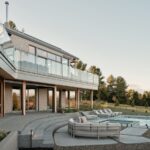 Vonkajší areál s modrým bazénom, svetlými ležadlami, betónovými schodmi a modernou architektúrou v prírode.