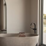 Svetlá kúpeľňa s oválnou kamennou vaňou.