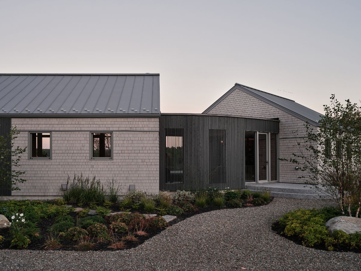 Sivé oceľové strechy a vonkajšie obloženie z cédrového dreva splývajú s okolitými kopcami a poľami