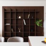 Tmavohnedá drevená policová zostava s minimalistickými dekoráciami a zelenou rastlinou.