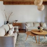 Dve svetlé látkové pohovky na koberci s vintage vzorom a pri drevených konferenčných stolíkoch.