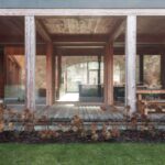 Presklená fasáda s nosnými drevenými stĺpmi nad drevenou palubou terasy.