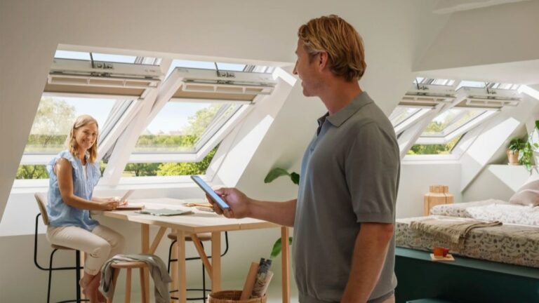 Muž a žena v podkrovnej izbe pod otvorenými strešnými oknami.