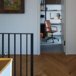 Chodba na poschodí s drevenou podlahou a otvorenými dverami do domácej pracovne.