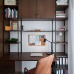 Integrovaný pracovný kút s tmavohnedou policovou zostavou so stolom a koženým kreslom.