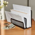 Organizér na poštu na drevenom stolíku vedľa bankoviek, vázy na kvety a kľúčov.