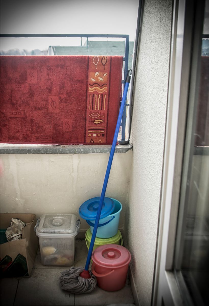Vedrá a mop na balkóne s kobercom preveseným cez zábradlie.