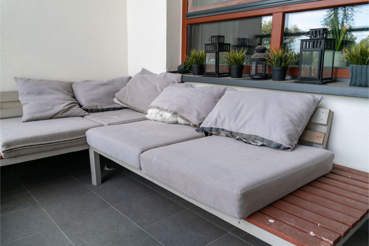 Sedačka na balkóne s natrhnutými vankúšmi, z ktorých trčí výplň.