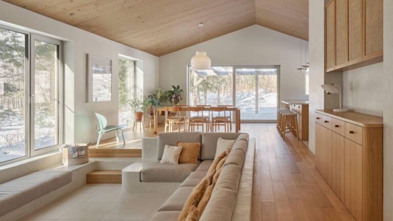 Svetlý otvorený interiér s dreveným latkovým stropom, vstavanou béžovou sedačkou a veľkými presklenými stenami.