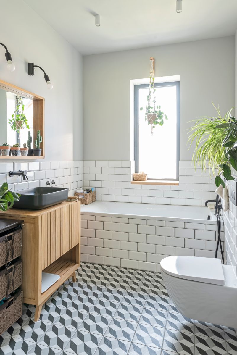 Kúpeľňa s obkladom v štýle metro, murovanou vaňou a čiernym umývadlom na drevenej skrinke.