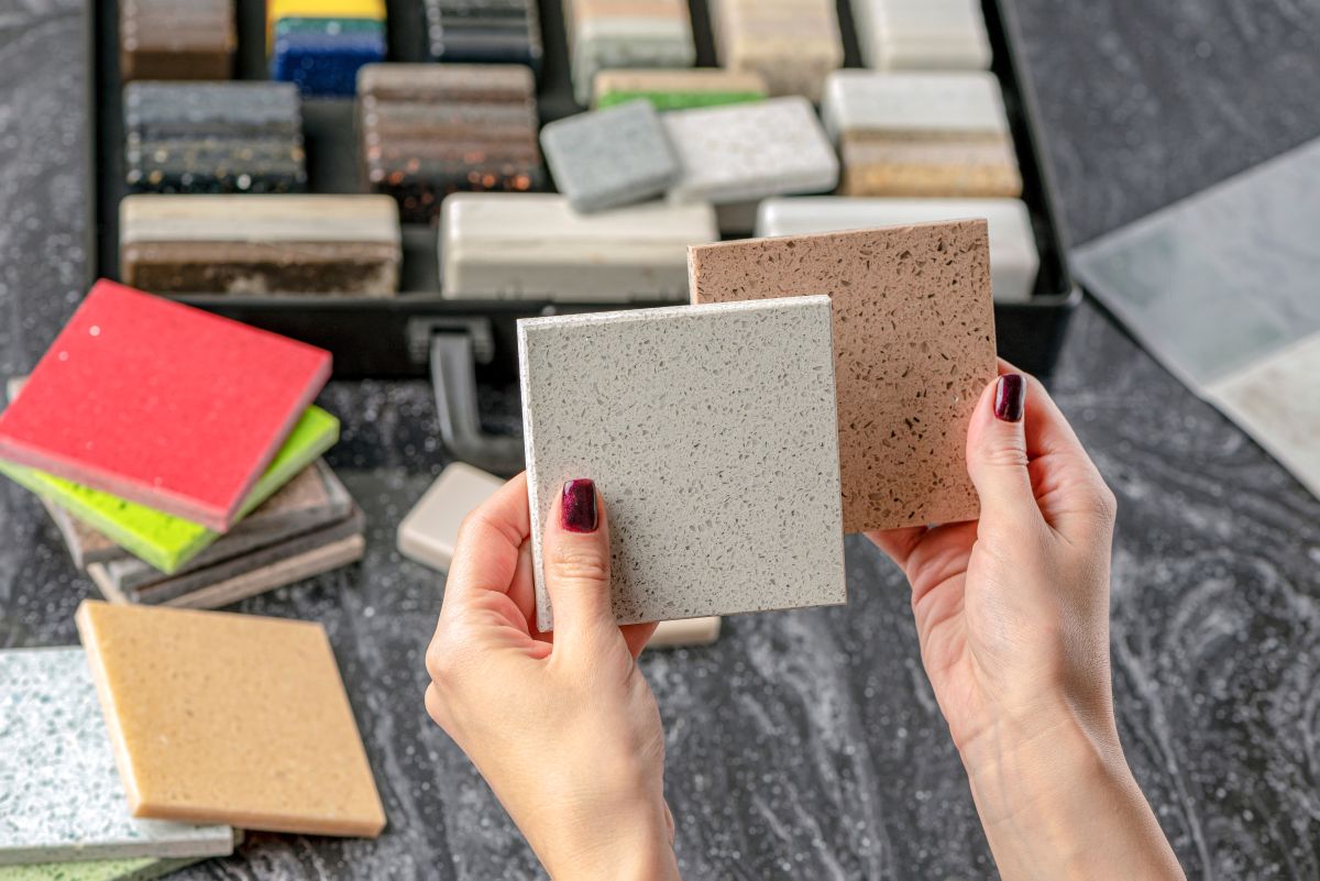 Ženské ruky držia vzorku materiálov na obklady do kúpeľne.