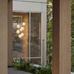 Terasa s drevenými stĺpmi, skleneným zábradlím a guľovými svietidlami.