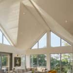 Obývacia izba s kazetovým stropom, béžovou sedačkou a žltými kreslami.