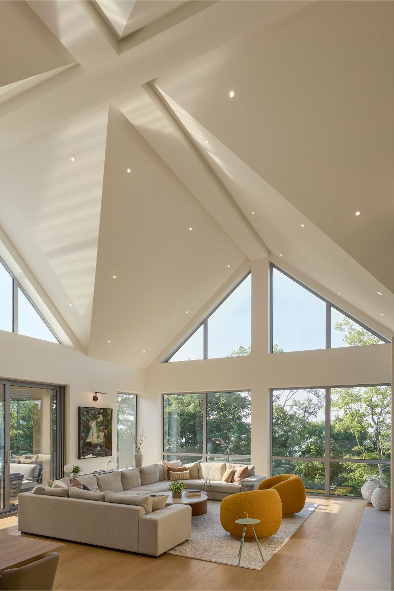 Obývacia izba s kazetovým stropom, béžovou sedačkou a žltými kreslami.