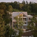 Moderný dom so zložitou strechou v tvare kríža a svetlou fasádou.