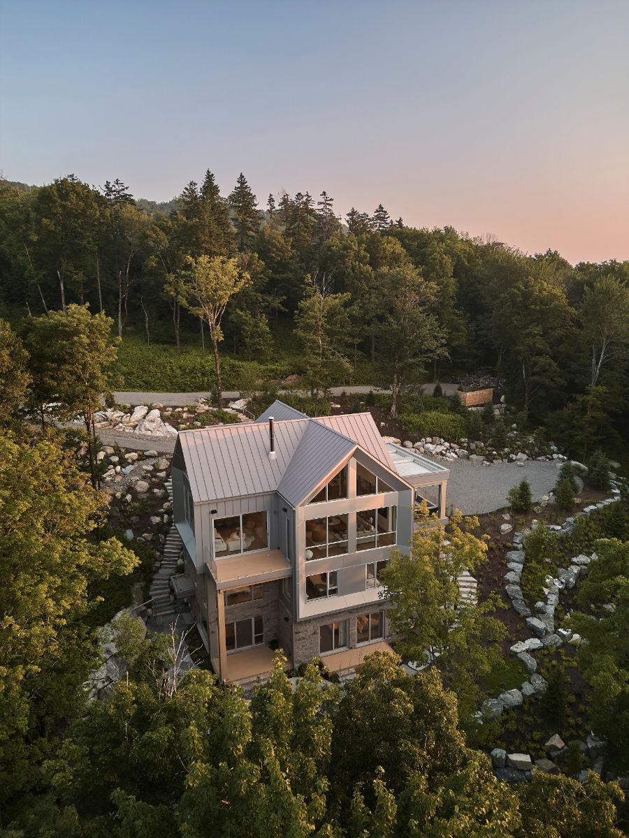 Vila s plechovou strechou v tvare kríža a kaskádovitou záhradou v lese.