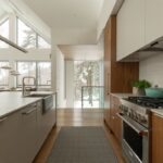 Kuchyňa s drevenými a bielymi skrinkami a bielym ostrovčekom.