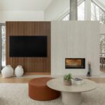 Obývacia izba s lamelovou stenou, svetlosivým moderným krbom a drevenou podlahou.