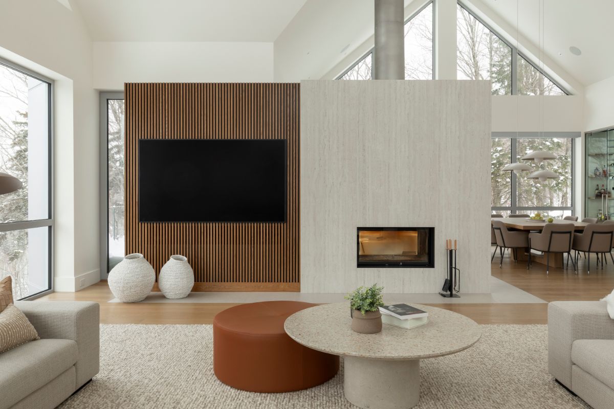 Obývacia izba s lamelovou stenou, svetlosivým moderným krbom a drevenou podlahou.
