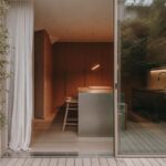 Pohľad do kuchyne s nerezovým ostrovom, drevenými barovými stoličkami, vysokými skriňami z dubovej dyhy a preskleným vstupom na terasu.