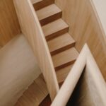 Schodisko s drevenými stupňami aj zábradlím a svetlou omietkou.