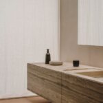 Kúpeľňa s umývadlom aj skrinkou z travertínu, zrkadlom a kúpeľňovými doplnkami.